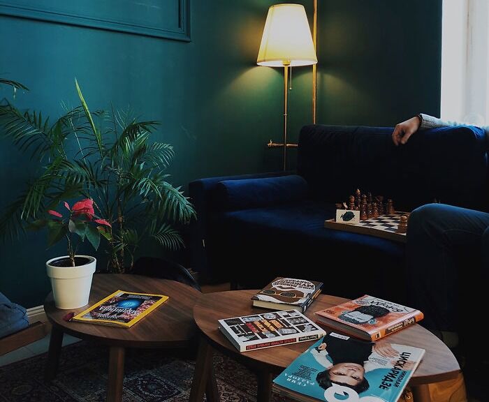 Cozy living room with dark sofa, chessboard, and magazines, illuminated by floor lamp—ideal for creative decoration ideas.