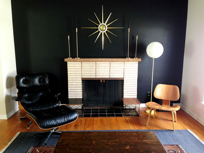 Creative decoration inspiration: modern living room with black accent wall, stylish chairs, and sunburst clock above fireplace.
