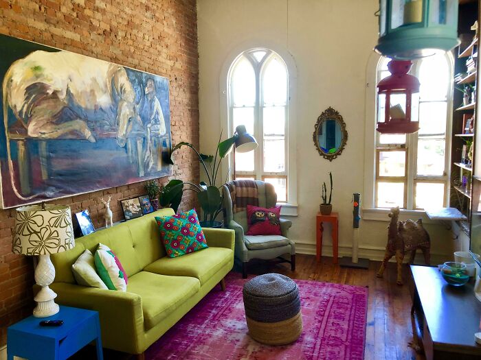 Colorful creative living room decor with a green couch, vibrant cushions, large painting, and eclectic accessories.