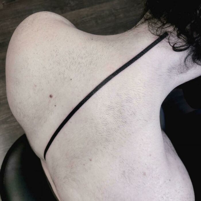 Black minimal line tattoo on spine