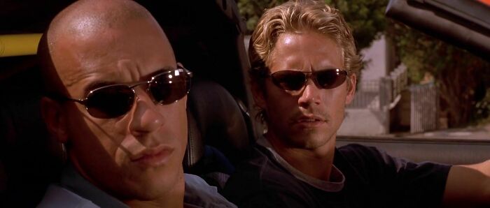 Two men, wearing sunglasses in a car, representing an iconic best friend duo in a movie scene.