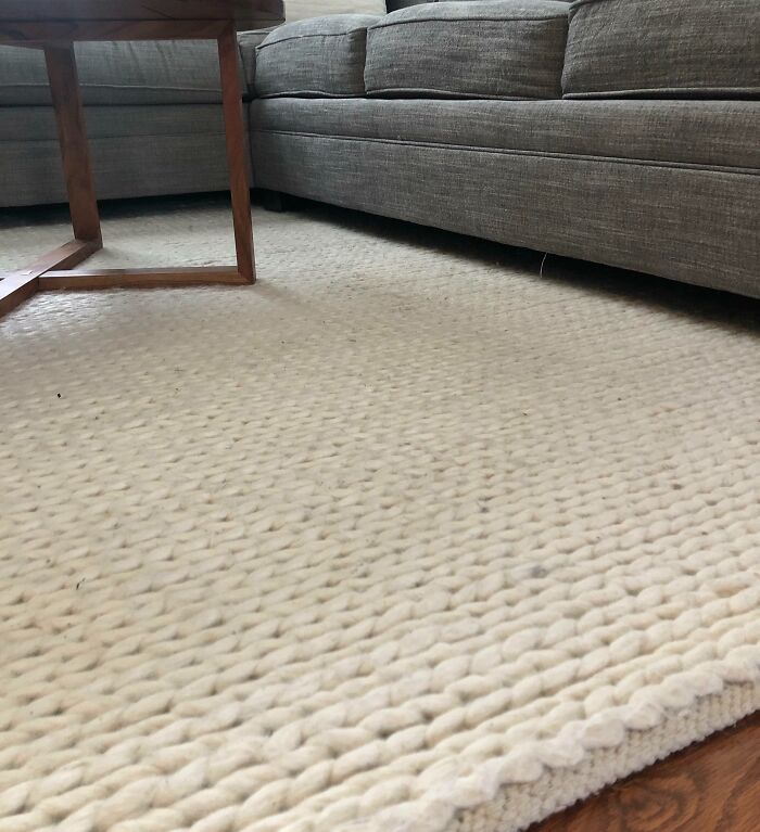 Cream knitted rug decorating a modern living room with gray couches.