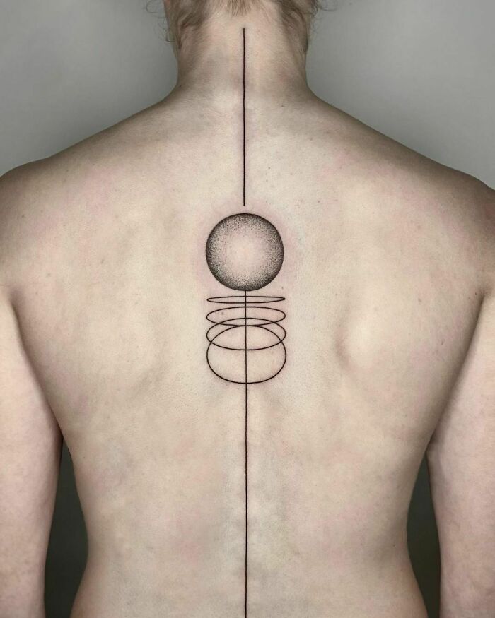 Elegant spine tattoo with geometric shapes on a person's back, featuring a straight line and circular patterns.