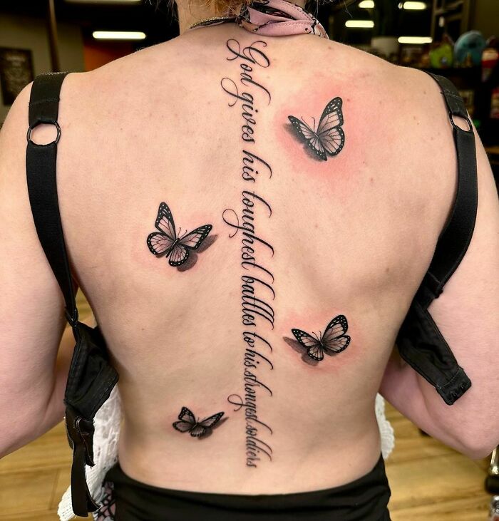 Spine tattoo with script and butterflies on a person's back.