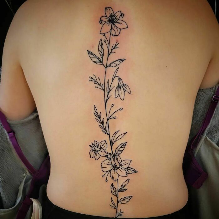 Black linear flowers tattoo on spine