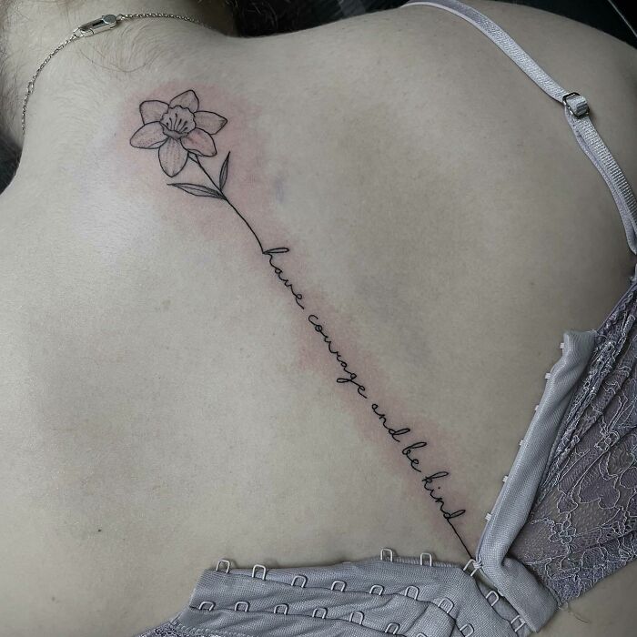 Flower and lettering tattoo on the spine