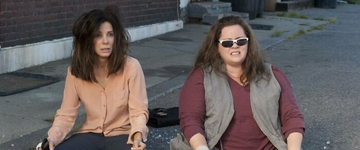 Two women sitting on a sidewalk, capturing an iconic best friend duo moment.