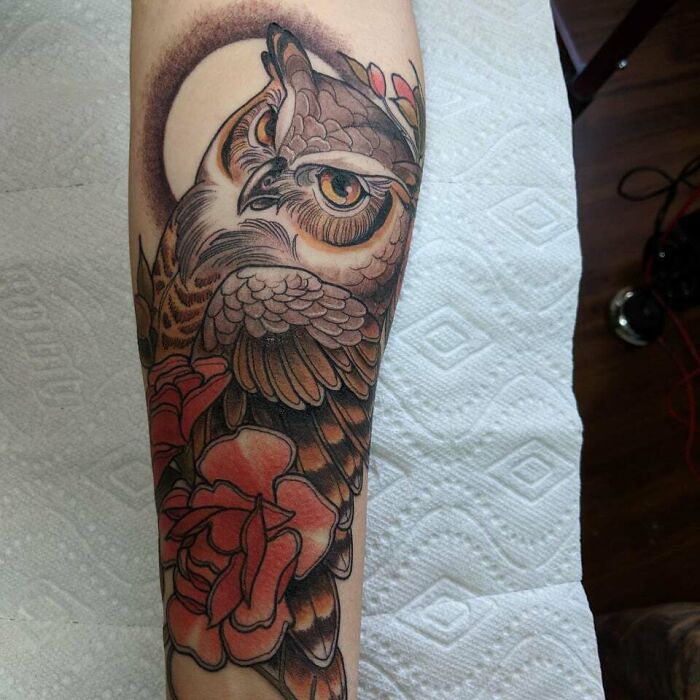 Owl tattoo on forearm featuring vibrant roses and intricate details. Perfect inspiration for animal tattoo ideas.
