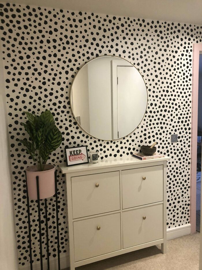 Creative decoration idea featuring a polka-dotted wall with a round mirror and chic storage unit.