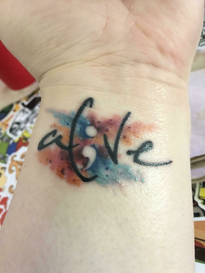 Word tattoo with negative semicolon on left wrist