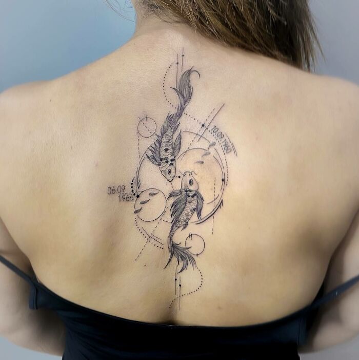 Two fishes with dates tattoo on the back 