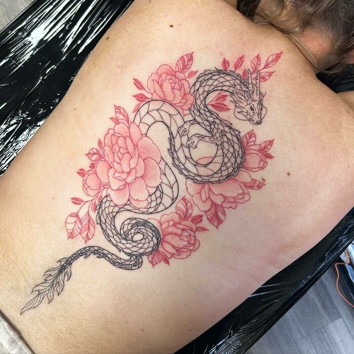 Large black linear dragon and red flowers tattoo on the back