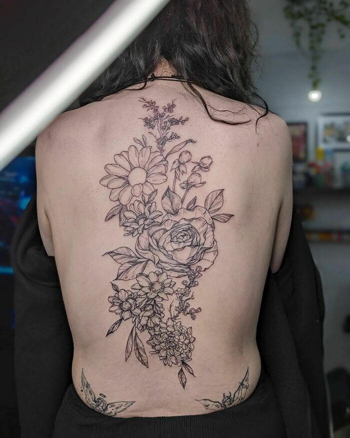 Floral spine tattoo design featuring roses and daisies on a person's back.