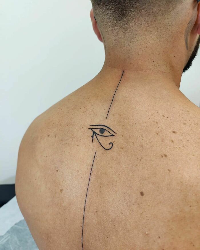 Eye of Horus and vertical minimal black line tattoo on spine