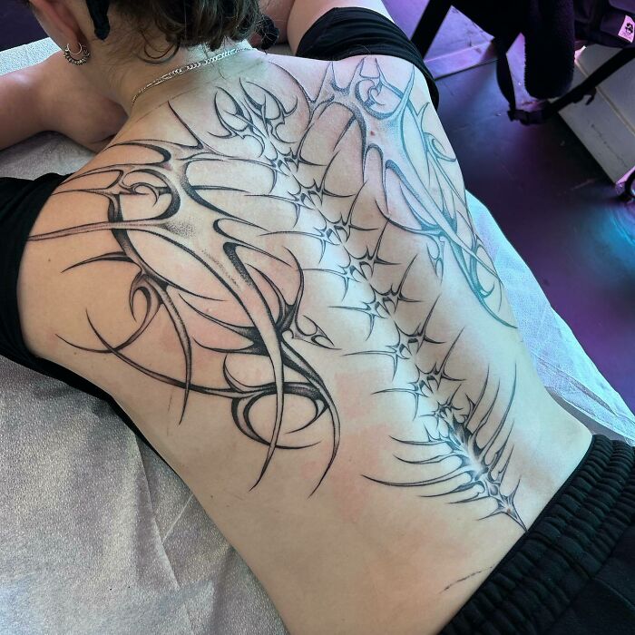 Elegant spine tattoo with intricate linework on a person's back, showcasing a unique design.