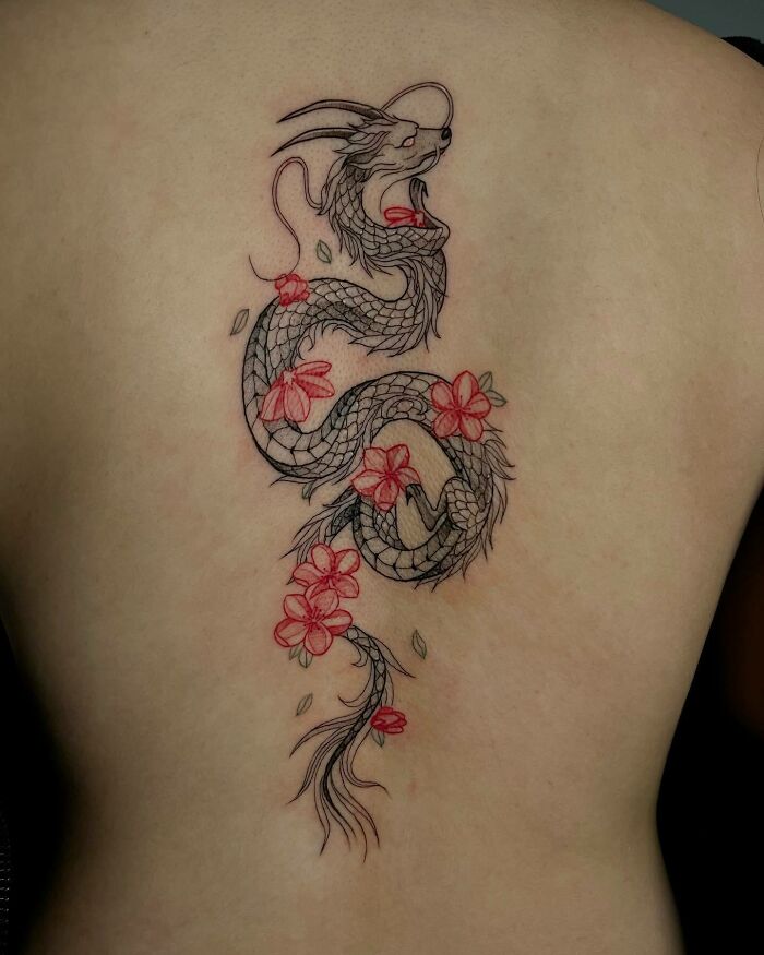 Elegant spine tattoo featuring a dragon with floral accents in black and red ink design.