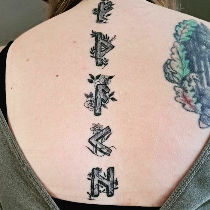 Black runes tattoo on spine