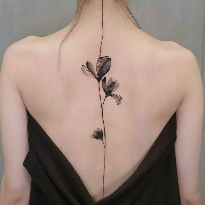 Black poppy and line spine tattoo