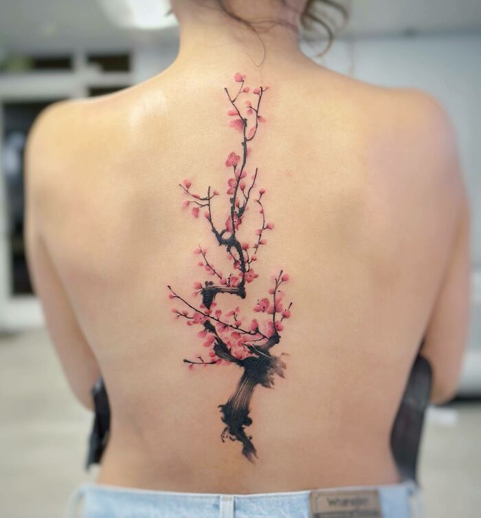 Large pink blossom branch tattoo on spine
