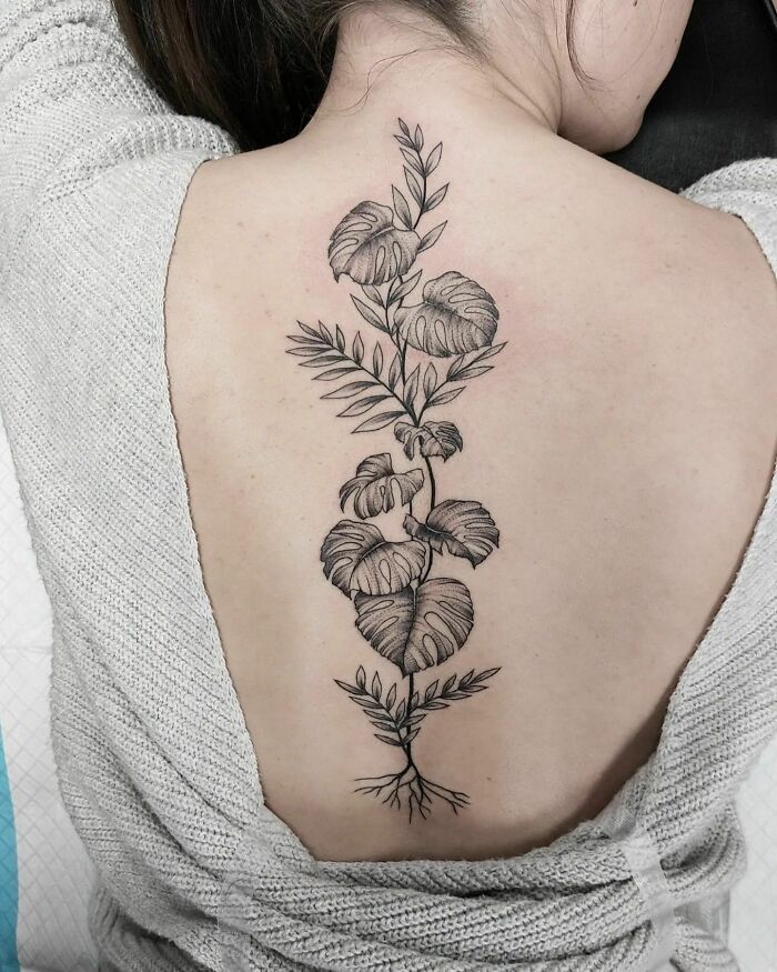 Floral spine tattoo design on woman's back, displayed in black ink.