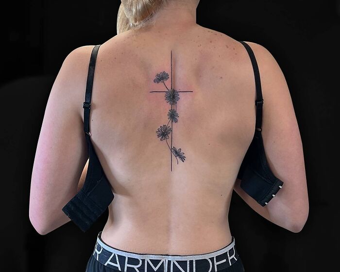 Elegant spine tattoo featuring floral design on a woman's back.
