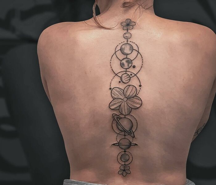 Elegant spine tattoo featuring celestial designs and floral elements.