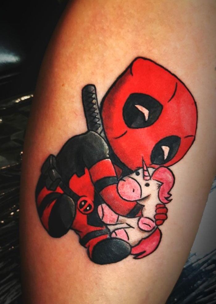 Chibi Deadpool tattoo hugging a pink unicorn, showcasing Marvel superhero design.
