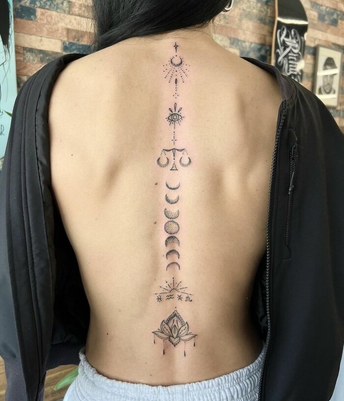 Moon phases and lotus along the spine tattoo