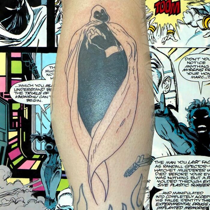 Marvel tattoo featuring a cloaked superhero character on arm, set against a comic book page background.
