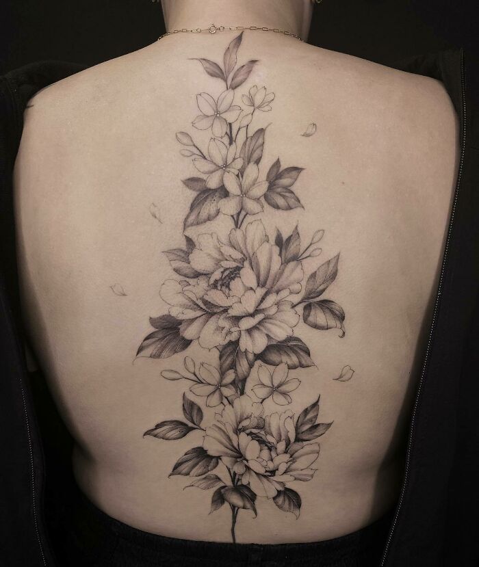 Elegant floral spine tattoo featuring detailed blossoms and leaves on a person's back.