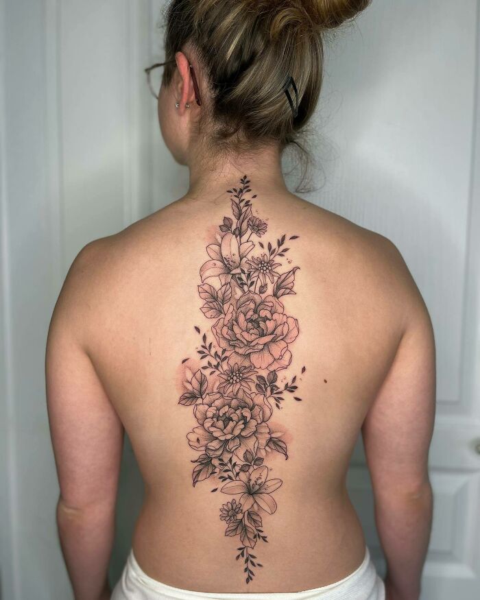 DIfferent flowers and small leaves along the spine tattoo 