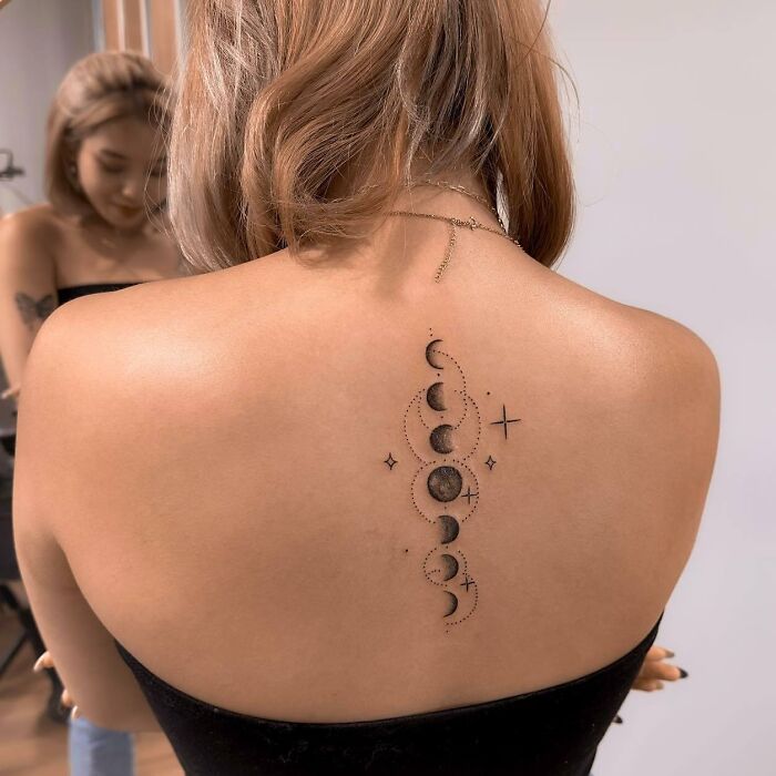 Moon phases spine tattoo on girl’s back