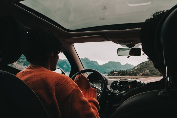 man in an orange sweater driving the car