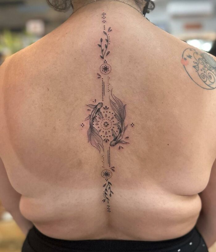 Unalome tattoo on the upper back.