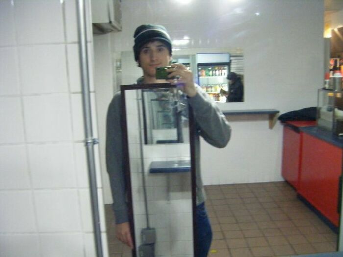 Man standing with a mirror taking a picture on front of a mirror