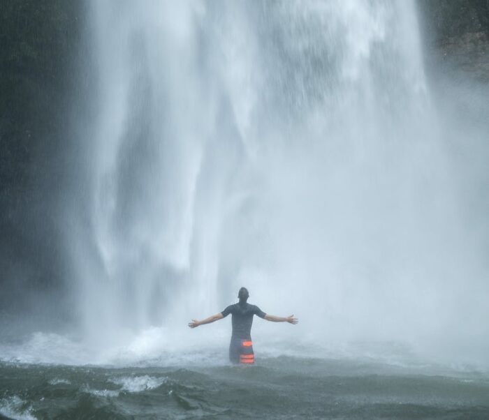 man standing under the waterfall