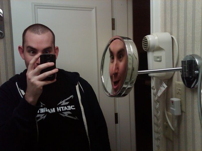 Funny mirror reflection of a man taking a picture 