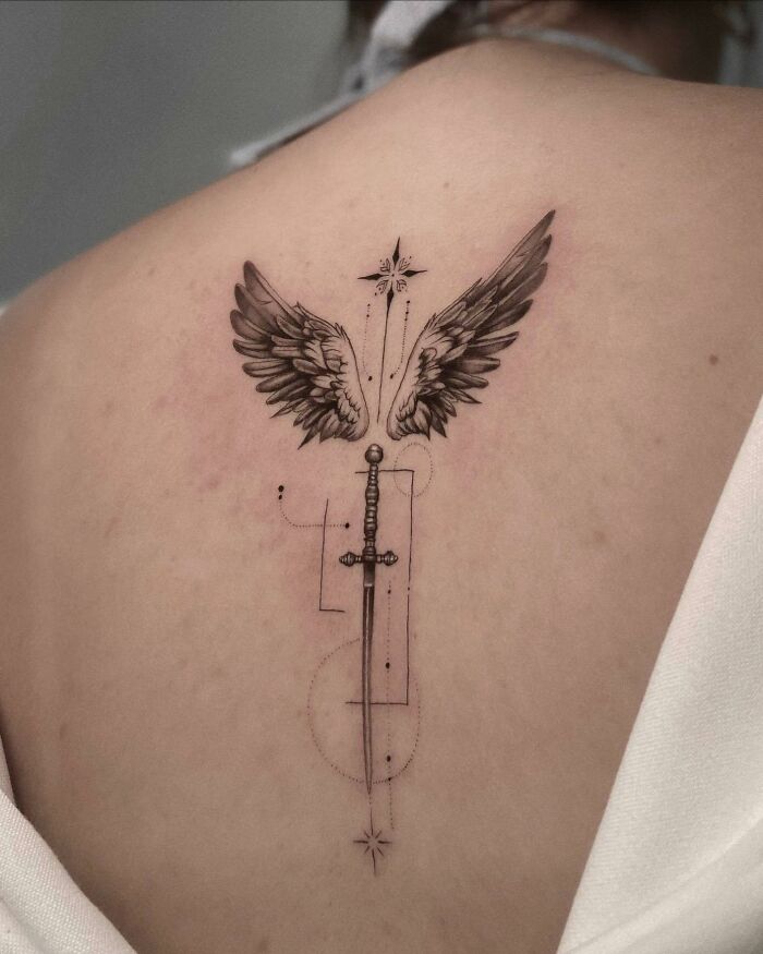 Wings and sword along the spine tattoo