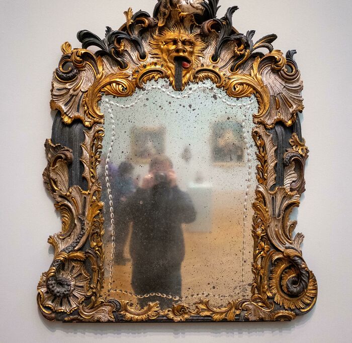 Person taking a picture of a 300 year old mirror 
