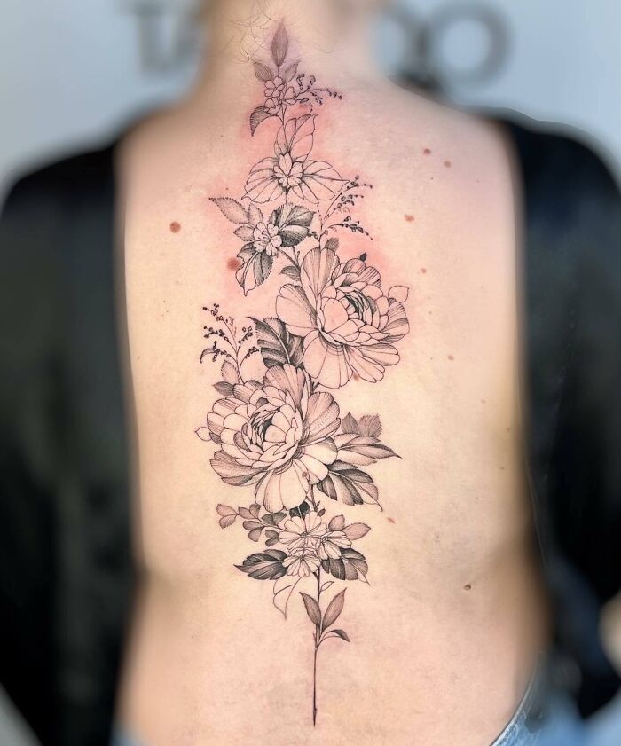 Elegant spine tattoo with intricate floral design, showcasing fine lines and shading.