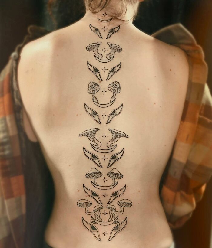 Elegant spine tattoo featuring abstract designs and decorative patterns on a person's back.