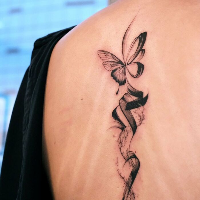 Black brush stroke tattoo with a butterfly on the spine