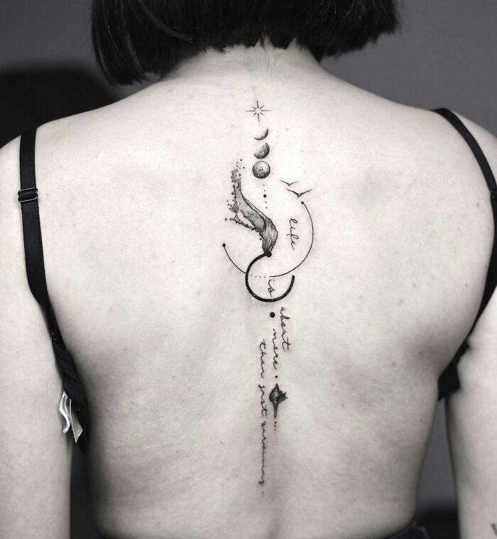 Moon phases, wave, symbols and inscription spine tattoo 