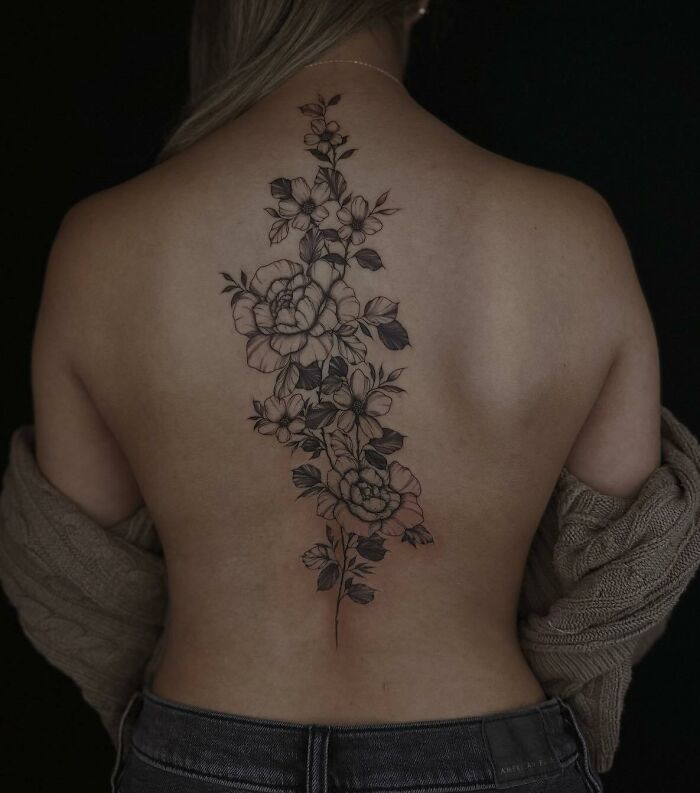 Floral spine tattoo design on a woman's back, showcasing elegant artwork.