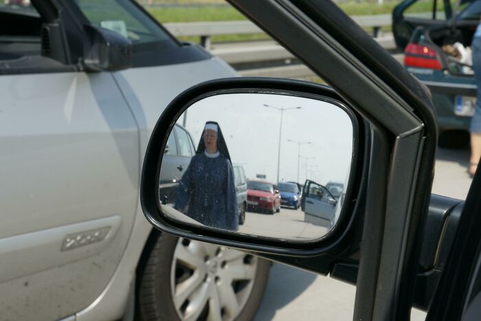 Nun seen on a car's mirror reflection 