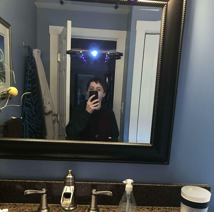 Boy taking a picture of himself and a drone in the bathroom 