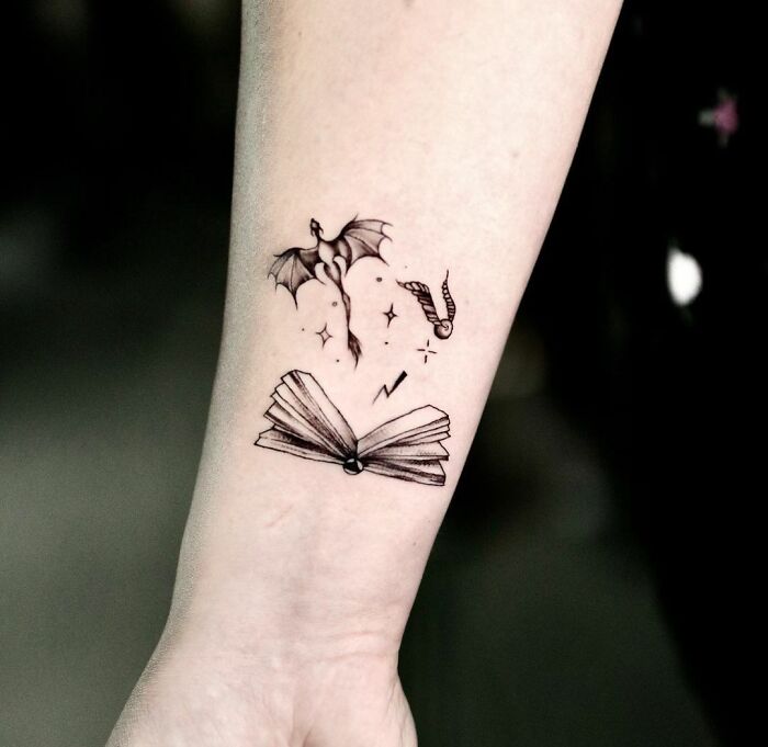 Harry Potter tattoo featuring a book, dragon, and lightning bolt on an arm.