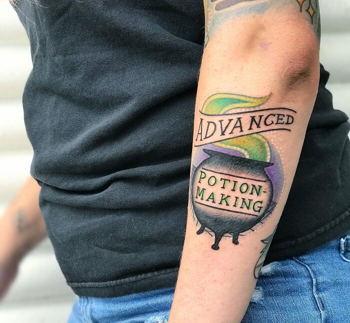 Harry Potter tattoo featuring a colorful cauldron with "Advanced Potion-Making" text on arm, celebrates wizarding world magic.