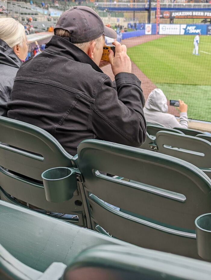 A Man Using A Disposable Film Camera To Take Pictures At Aaa Baseball Game Today