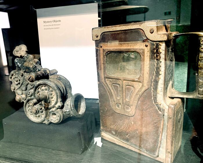 Two Mystery Objects Found In The Gwalia Ghost Town Museum Near The Outback West Australian Mining Town Of Leonora. An Ornate Cast Iron Case With A Hole And A Turnkey(?), And A Leather & Metal Box With A Handle, Button And Transparent Panel